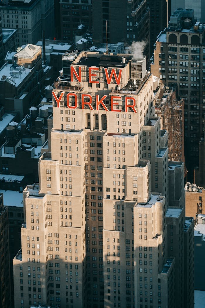 Drone view of modern multistory hotel located on street with residential houses in megapolis with bright sunlight in New York